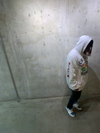 a person wearing a white hoodie standing on a concrete floor